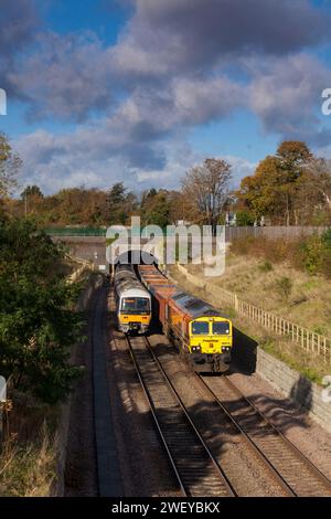 Freightliner-Lokomotive der Baureihe 66 mit einem leeren Güterzug aus Kastenwagen, der an einer Chiltern Railways-Baureihe 165 im Wolvercote Tunnel in Oxford vorbeifährt Stockfoto