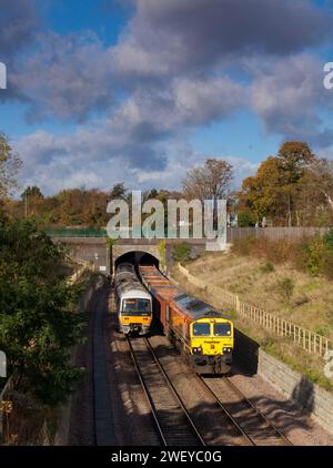 Freightliner-Lokomotive der Baureihe 66 mit einem leeren Güterzug aus Kastenwagen, der an einer Chiltern Railways-Baureihe 165 im Wolvercote Tunnel in Oxford vorbeifährt Stockfoto