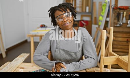 afroamerikanerin mit Dreadlocks, die eine Schutzbrille in einer Tischlerei trägt Stockfoto