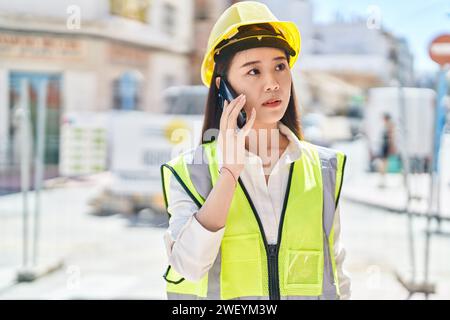 Junge chinesische Architektin, die auf der Straße mit einem Smartphone spricht Stockfoto