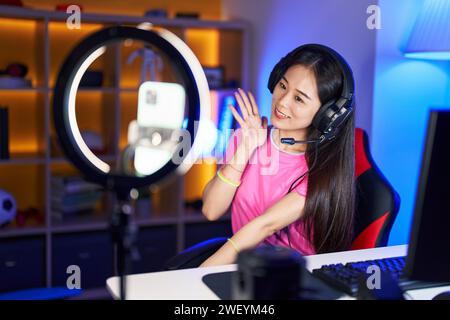 Junge chinesin nimmt Vlog-Tutorial mit Smartphone zu Hause auf und feiert Leistung mit glücklichem Lächeln und Siegerausdruck mit erhobener Hand Stockfoto