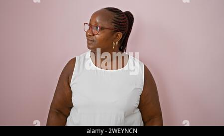 Ernsthafte aftere afroamerikanische Frau, die zur Seite blickt, zeigt eine coole, entspannte Atmosphäre, isoliert vor einer leuchtend rosa Wand. Lifestyle in Übergröße Stockfoto