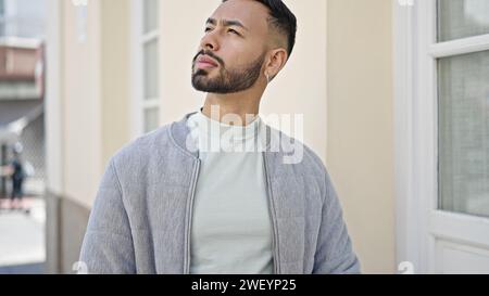 Junger spanischer Mann, der auf der Straße mit ernstem Gesichtsausdruck steht Stockfoto