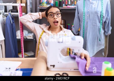 Junge arabische Schneiderin Designerin, die im Atelier arbeitet, skeptisch und nervös, runzelnd verärgert wegen Problemen. Negative Person. Stockfoto