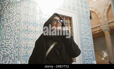 Eine lächelnde Frau mit Gläsern genießt die komplizierten Fliesen im historischen topkapi-Palast in istanbul. Stockfoto