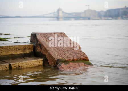 Budapest, Ungarn - 30. Dezember 2023: Überflutete Steintreppe am Donauufer. Kettenbrücke im Hintergrund. Stockfoto