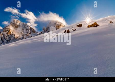 Auf einem Hügel im Val Venegia oberhalb des Passes Rolle, links der Gipfel der Cima della Vezzana und des Cimon della PAL, scheint die Sonne über den Schneehaufen Stockfoto