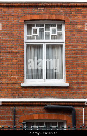 Klassische weiße Fenster mit typischer londoner Architektur mit roter Backsteinmauer Stockfoto