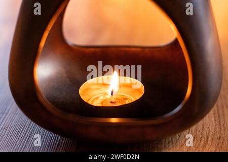 Eine Kerze in einem Kerzenhalter zum Erwärmen des duftenden Wassers für die Aromatherapie Stockfoto