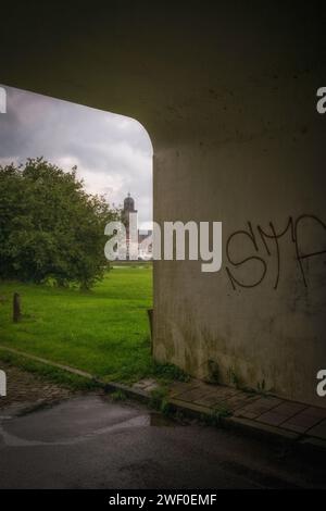 Ein Graffiti-Kunstwerk in einem Tunnel in einem Park, mit grünem Gras und ein paar Bäumen im Hintergrund Stockfoto