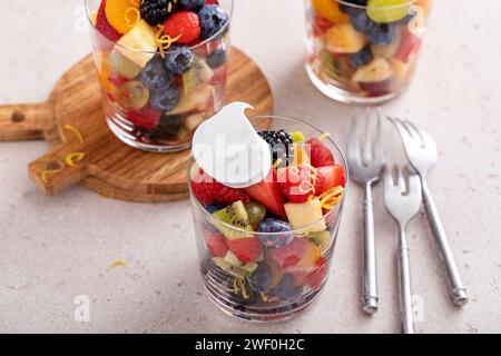 Gesunder Obstsalat, serviert in einzelnen Tassen mit Banane, Ananas, Beeren, Orangendressing und frischer Minze Stockfoto