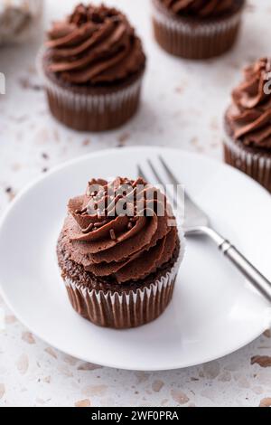 Schokoladen-Cupcakes mit geschlagener Schokoladenganache und Schokoladenstreuseln Stockfoto