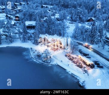 Aus der Vogelperspektive beleuchtete Häuser in einem verschneiten Dorf bei Nacht Stockfoto