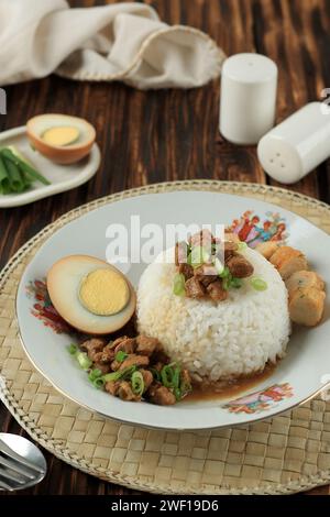 Nasi Bakmoy Ayam, gedämpfter Reis mit Sojasauce gebratenes Hühnchen, halbgekochtes Ei und Garnelenkuchen. Stockfoto