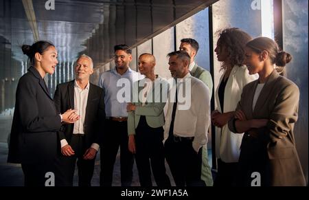 Asiatische Teamleiterin hält eine Motivationsrede vor Mitarbeitern verschiedener formeller Fachkräfte. Stockfoto