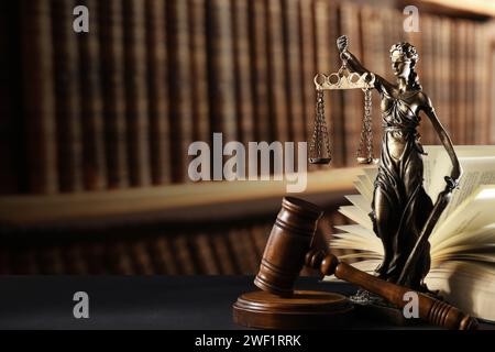 Gesetz. Statue von Lady Justice, Hammer und offenes Buch auf schwarzem Tisch drinnen, Platz für Text Stockfoto
