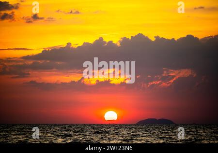 Feuriger Horizont, dramatischer Sonnenuntergang im Ozean in lebendigen Farben über dunklem Wasser, atemberaubendes Naturfoto, das die Kunstfertigkeit des ruhigen Spektakels der Abenddämmerung reflektiert und Stockfoto