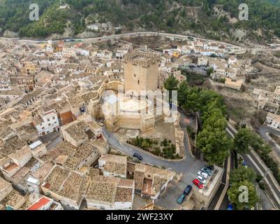 Aus der Vogelperspektive auf das Schloss Moratalla in der Provinz Murcia, Spanien, das das Dorf mit einem großen quadratischen Turm und einem schön restaurierten Denkmal aus dem Mittelalter dominiert Stockfoto