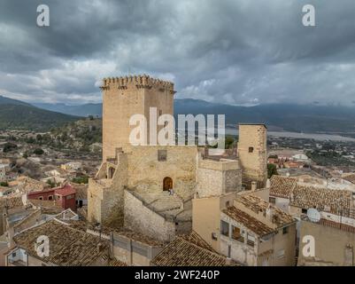 Aus der Vogelperspektive auf das Schloss Moratalla in der Provinz Murcia, Spanien, das das Dorf mit einem großen quadratischen Turm und einem schön restaurierten Denkmal aus dem Mittelalter dominiert Stockfoto