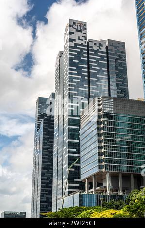 Singapur, 24. Januar 2024: Wolkenkratzer, Symbole der globalen Wirtschaft, erheben sich gegen blauen Himmel und Wolken. Hoch aufragende Strukturen verkörpern die Dominanz des Unternehmens. Stockfoto