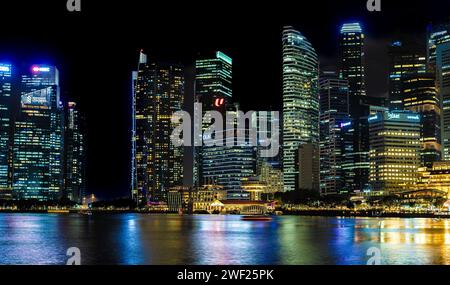 Singapur, 24. Januar 2024: Singapurs Stadtteil Marina Bay erleuchtet die Nacht, das Leuchten der Wolkenkratzer. Lebendige Lichter verwandeln die Stadtlandschaft in Mesmerizin Stockfoto