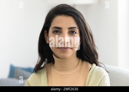 Glückliche, schöne lateinische Frau, die mit freundlichem Lächeln in die Kamera schaut Stockfoto