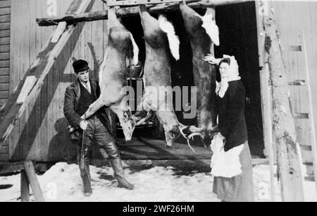 MA und Pa posieren mit ihrer Hirschernte in der Scheunentür in Wisconsin, CA. 1910. Stockfoto