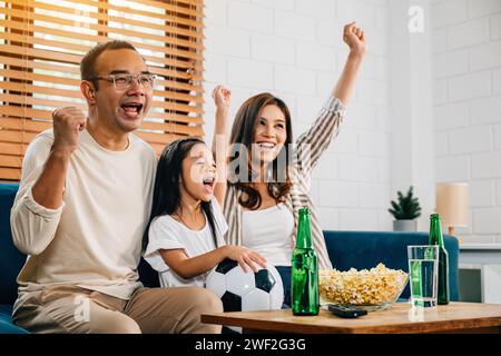Eine glückliche Familie genießt den Nervenkitzel eines Fußballspiels zu Hause Stockfoto
