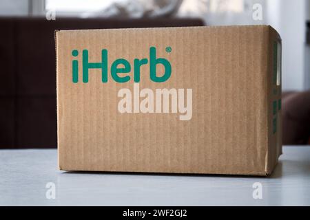Brauner Karton mit grünem Logo iHerb Store, auf dem Tisch. Online-Bestellung, Einkauf, Kauf von Vitaminen und Kosmetika. Paketannahme, Zustellung. Bischkek, Kirgisistan - 8. Dezember 2023 Stockfoto