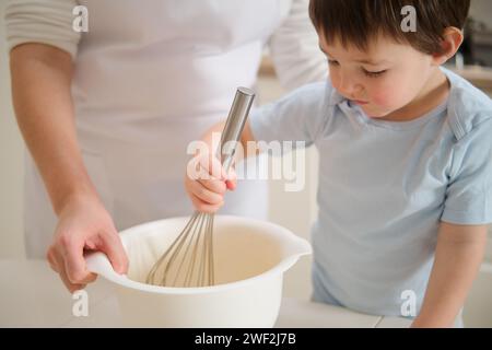 Baby Junge und seine Mutter, die in der Küche Teig quetschen. Prozess des Kochens von Pekannkuchen in der Küche für den amerikanischen Thanksgiving Day. Stockfoto