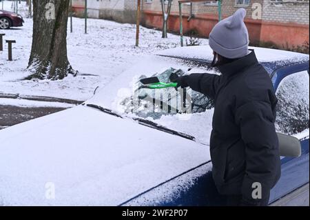 Schnee von der Windschutzscheibe entfernen, Eis abkratzen Stockfoto