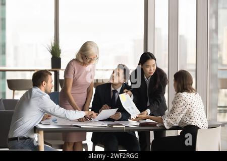 Multiethnisches Team von Kollegen, das Marketingberichte in Papierform analysiert Stockfoto