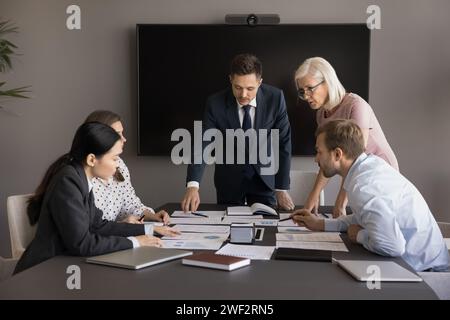 Fokussiertes, vielfältiges Geschäftsteam, das bei Vertriebsberichten kooperiert Stockfoto