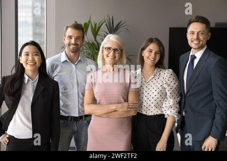 Reifer Geschäftsleiter und multiethnische jüngere Mitarbeiter lächeln in die Kamera Stockfoto