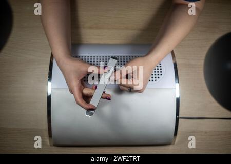 Porträt weiblicher Hände, während sie ihre eigenen Nägel manuell feilen und selbstgebaute Nägel schließen Stockfoto