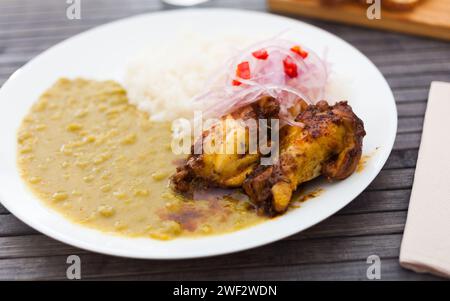 Hähnchenflügel mit Erbsenpüree, Reis und eingelegten Zwiebeln auf weißem Teller Stockfoto