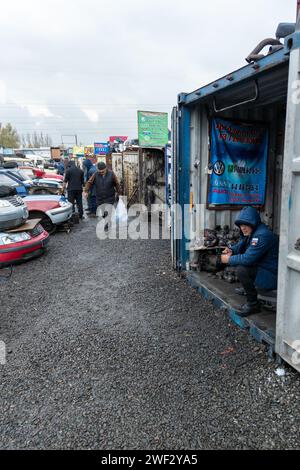 Mann, der Volkswagen Autoteile auf dem Freiluftmarkt für Gebrauchtteile in Kudaybergen, Bischkek, Kirgisistan verkauft Stockfoto