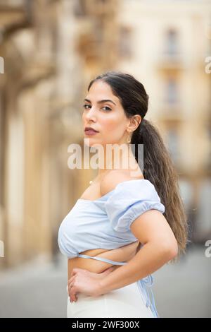 Ernsthafte Frau, Hände auf Hüften, die draußen in die Kamera schaut Stockfoto