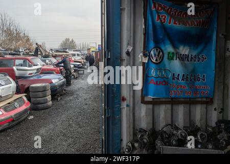 Mann, der Volkswagen Autoteile auf dem Freiluftmarkt für Gebrauchtteile in Kudaybergen, Bischkek, Kirgisistan verkauft Stockfoto