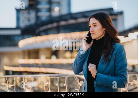 Professionelle Frau in blauem Blazer, die in urbaner Umgebung telefoniert. Stockfoto