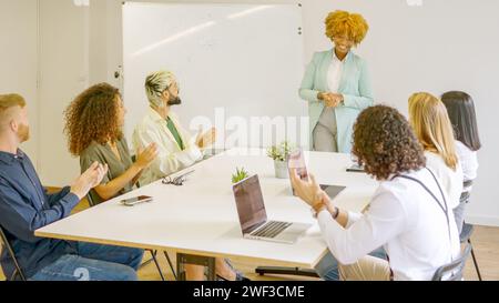 Kollegen applaudieren einer afrikanerin nach einer Präsentation Stockfoto