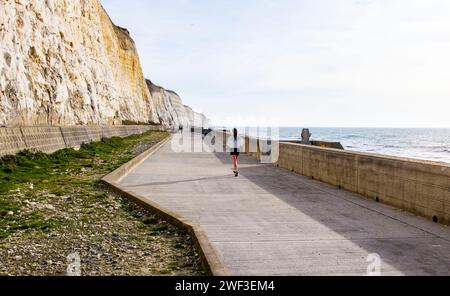 Brighton Großbritannien 28. Januar 2024 - Ein Läufer genießt die Wintersonne entlang des Unterkliffs Walk an der Brighton Marina, da für den Großteil Großbritanniens heute ein viel milderes Wetter als die letzten Tage prognostiziert wird: Credit Simon Dack / Alamy Live News Stockfoto