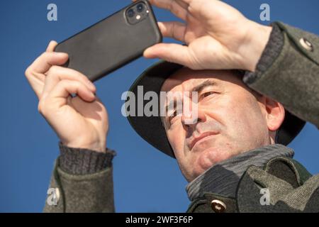 Hubert Aiwanger, filmt die Menschenmenge der Teilnehmer mit Handy, Kundgebung der Mittelstand steht auf, Theresienwiese, München, 28. Januar 2024 Deutschland, München, 28. Januar 2024, Hubert Aiwanger, stellvertretender Bayerischer Ministerpräsident, Vorsitzender der Freien Wähler, filmt mit seinem Smartphone die Menschenmenge für Social Media, Teilnehmer bei: der Mittelstand steht auf, Motto einer Protest-Kundgebung auf der Theresienwiese, Protest gegen die Politik der Ampelregierung, organisiert von einem Bündnis Hand in Hand für unser Land , mehrere tausend Teilnehmer, Teilnehmer, angesproc Stockfoto