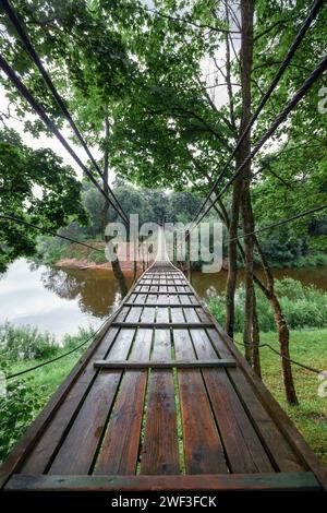 Hängende Affenbrücke über den Fluss Minija in Litauen. Schuss aus einem niedrigen Winkel direkt von vorne. Vertikales Foto. Stockfoto