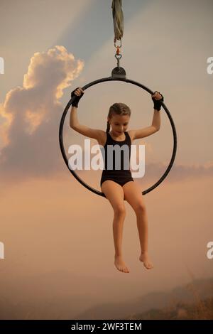 12 Jahre alte Turnerin, die draußen auf einem Luftkorb auftritt Stockfoto