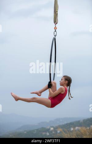 12 Jahre alte Turnerin, die draußen auf einem Luftkorb auftritt Stockfoto