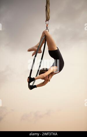 12 Jahre alte Turnerin, die draußen auf einem Luftkorb auftritt Stockfoto