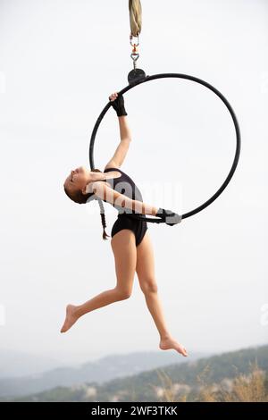 12 Jahre alte Turnerin, die draußen auf einem Luftkorb auftritt Stockfoto