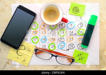 Kalender mit Geschäftsterminen, Smartphone, Textmarker, Kaffeetasse und Brille, monatlicher Zeitplan. Business-Konzept, Schlag die Uhr. Stockfoto