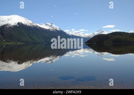 Schneebedeckte Berge Patagoniens spiegeln sich in den stillen Gewässern des Lago Cisnes in der Nähe der Villa O’Higgins an der Carretera Austral. Stockfoto